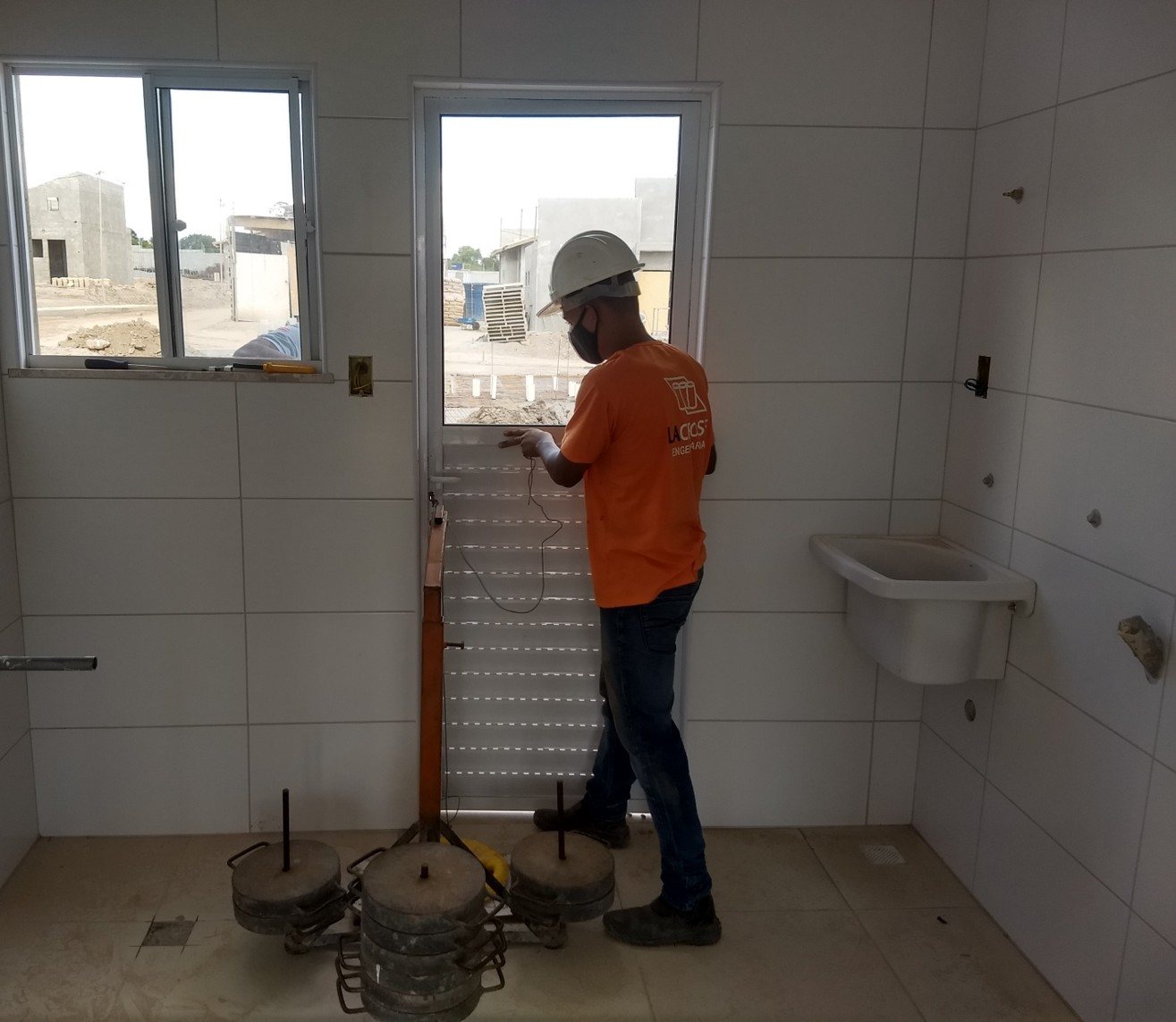 Técnico da LACROSE instrumenta porta com contrapesos para o ensaio de ações transmitidas por portas (fechamento brusco), da norma de desempenho.