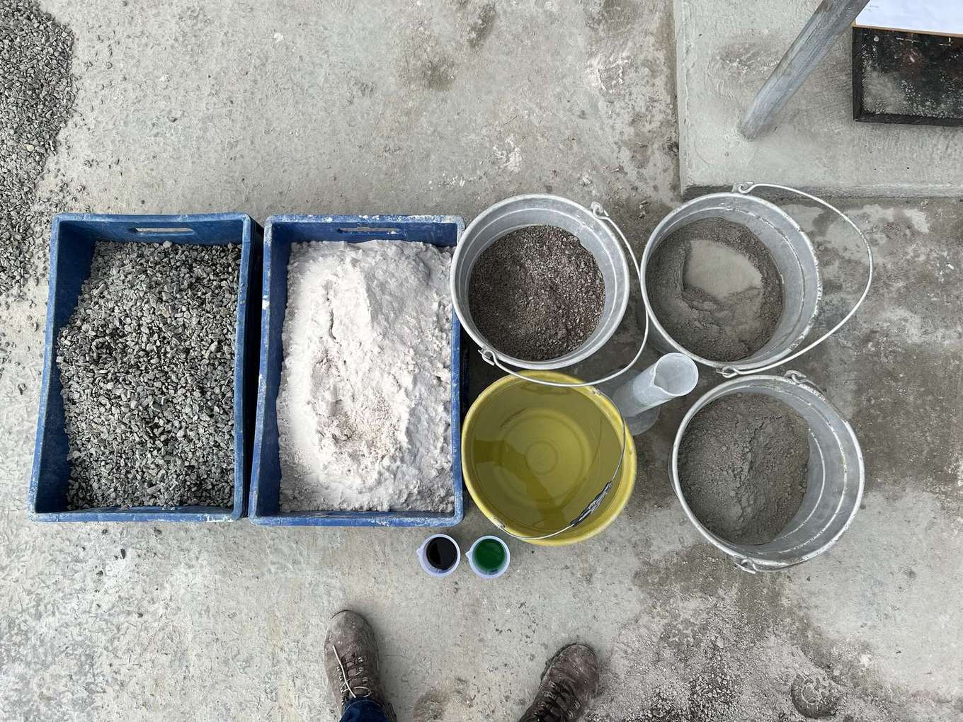 Materiais separados para estudo de dosagem em campo: baldes de cimento e agregados, proveta e caixas de areia e brita.