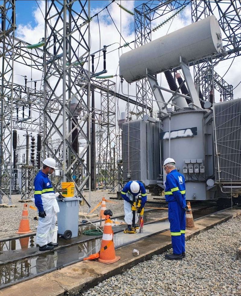Equipe com EPI completo executa a extração de testemunho na laje junto ao transformador da subestação de energia.
