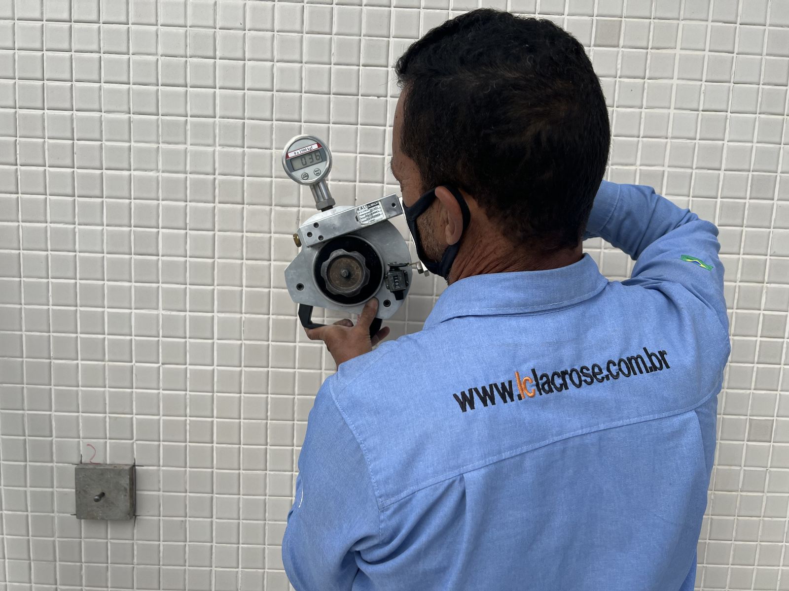 Técnico da LACROSE opera o dinamômetro de arrancamento sobre revestimento de pastilhas cerâmicas no ensaio de aderência à tração em fachada.