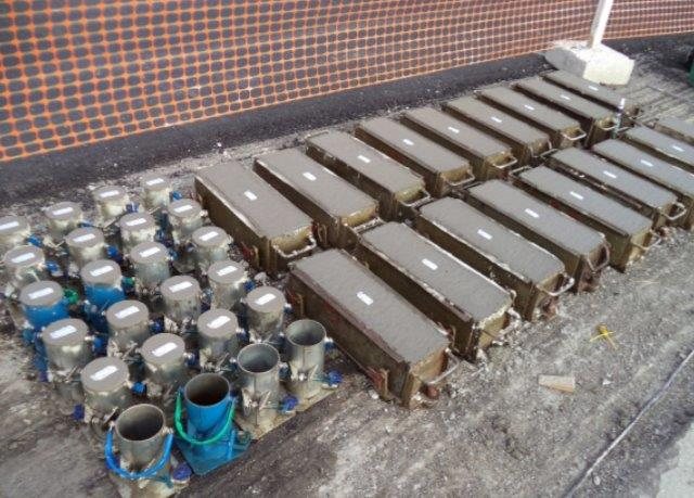 Corpos de prova prismáticos de concreto e moldes cilíndricos dispostos em bancada de laboratório, preparados para ensaios de controle tecnológico.